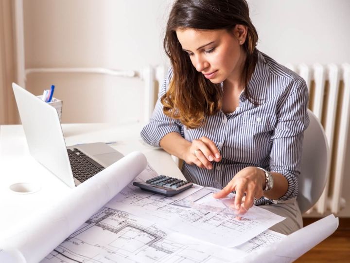 Home energy worker working on blueprint on laptop at home