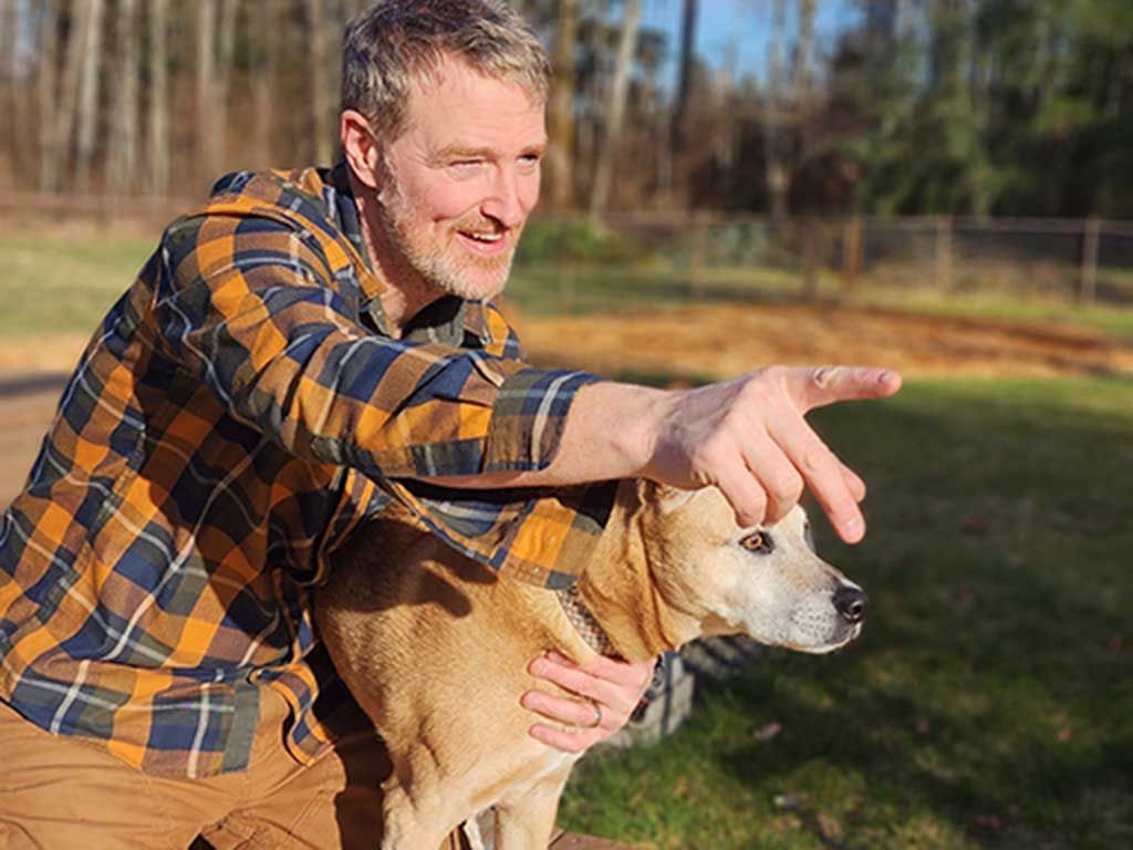 Founder Rick Martin showing his dog something by pointing off screen.